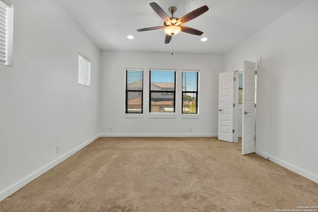 an empty room with windows and ceiling fan