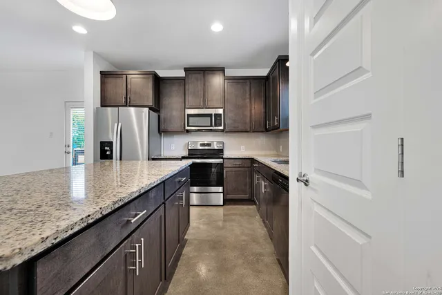 a kitchen with stainless steel appliances granite countertop a refrigerator a stove and a sink