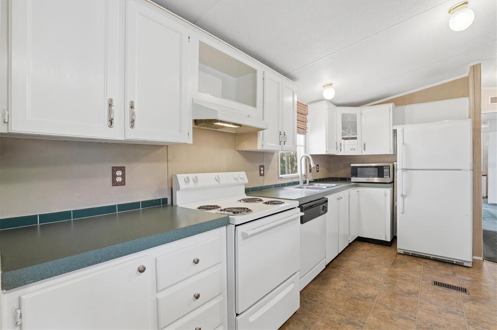 6169 Waverly Road Weeki Wachee, FL 34607 - Photo 29 of 51 a kitchen with granite countertop white cabinets and white appliances