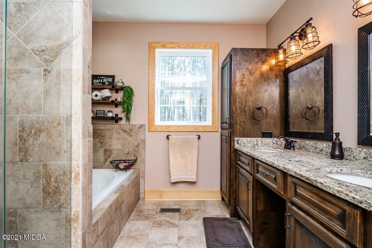 725 Taylor Road Juliette, GA 31046 - Photo 28 of 62 a bathroom with a granite countertop sink a mirror and a shower