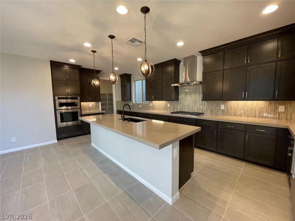 11 Rancho Maria Street Las Vegas, NV 89148 - Photo 9 of 27 Rich dark cabinetry and a long central island anchor this contemporary culinary space.