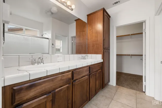 a bathroom with a granite countertop sink a mirror and shower