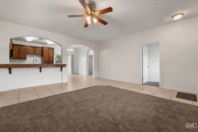 an empty room with a chandelier fan and a ceiling fan