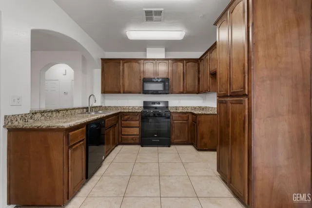 a kitchen with granite countertop a refrigerator stove top oven a sink and dishwasher