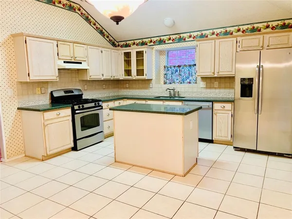 a kitchen with stainless steel appliances granite countertop a stove a sink and a refrigerator
