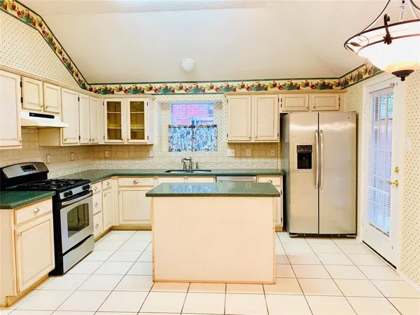 a kitchen with stainless steel appliances granite countertop a refrigerator and a stove top oven