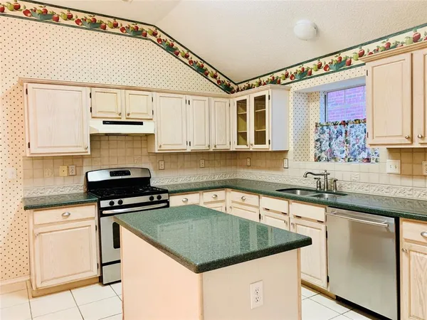 a kitchen with granite countertop a sink a stove and cabinets