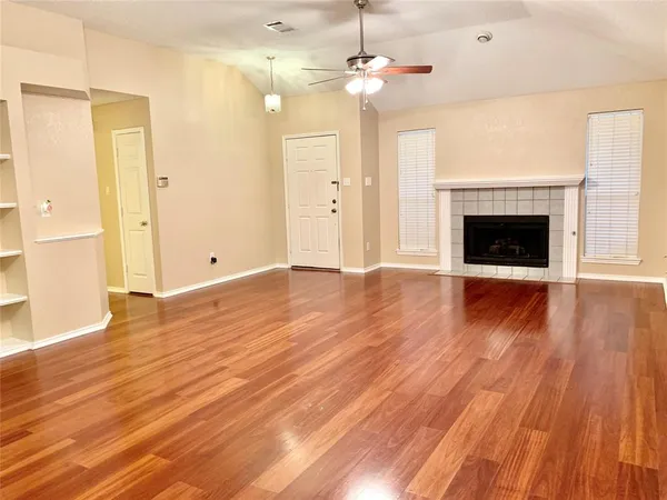 wooden floor fireplace and windows in an empty room