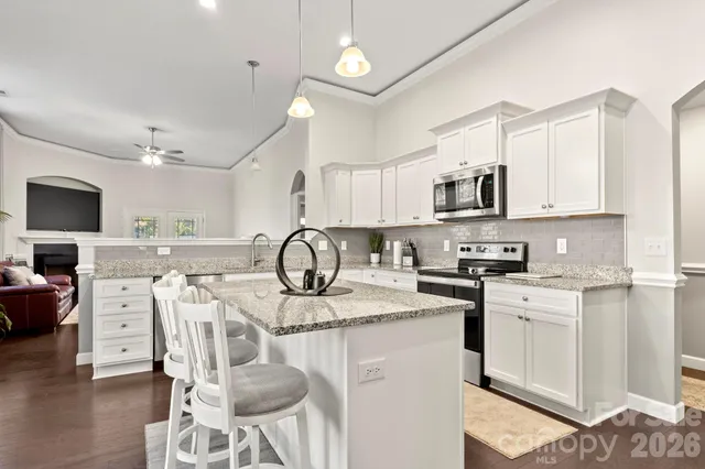 a kitchen with stainless steel appliances kitchen island granite countertop a sink a stove a dining table and chairs