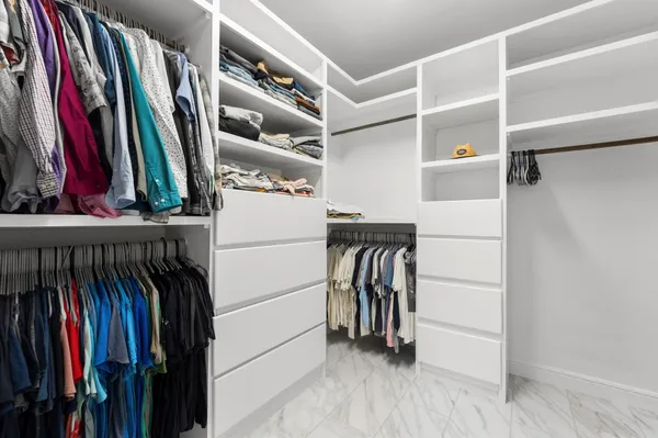 a view of walk in closet with clothes and shoes