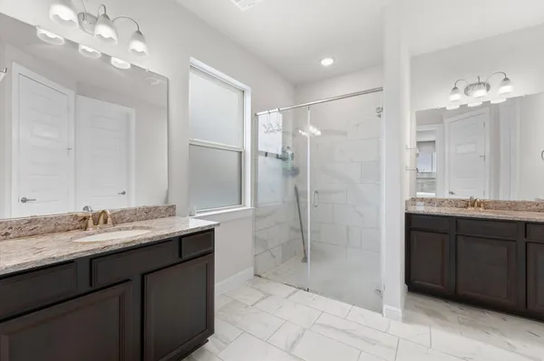 a bathroom with a granite countertop double vanity sink mirror and shower