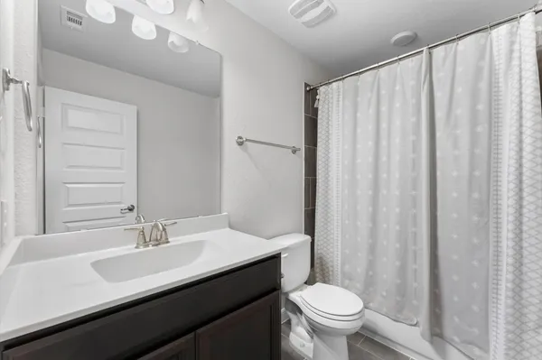 a bathroom with a sink a toilet and shower curtain