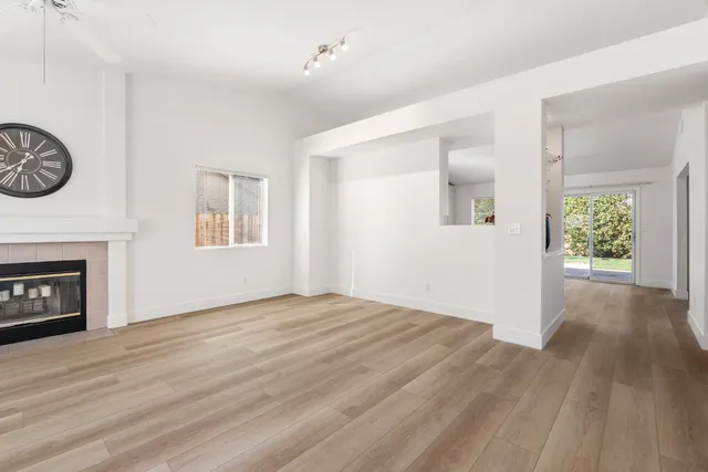 an empty room with windows and fireplace