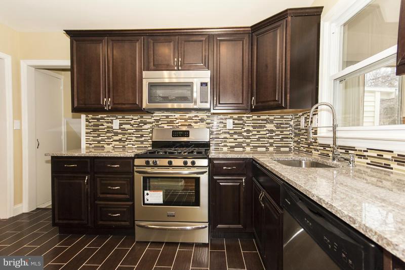 3405 Ripple Road Baltimore, MD 21244 - Photo 9 of 29 a kitchen with stainless steel appliances granite countertop wooden cabinets stove top oven and sink
