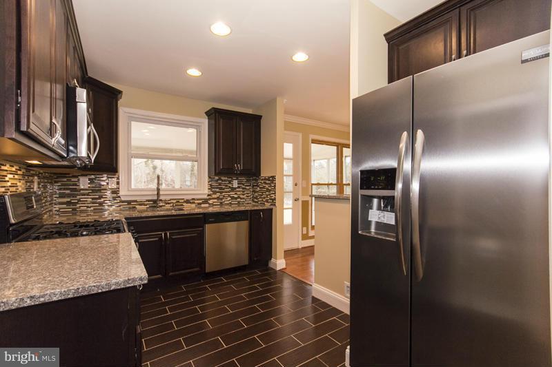 3405 Ripple Road Baltimore, MD 21244 - Photo 10 of 29 a kitchen with stainless steel appliances granite countertop a refrigerator a stove and a sink with wooden cabinets