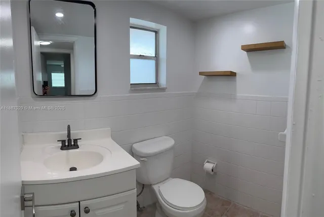 a bathroom with a toilet a sink a mirror and vanity