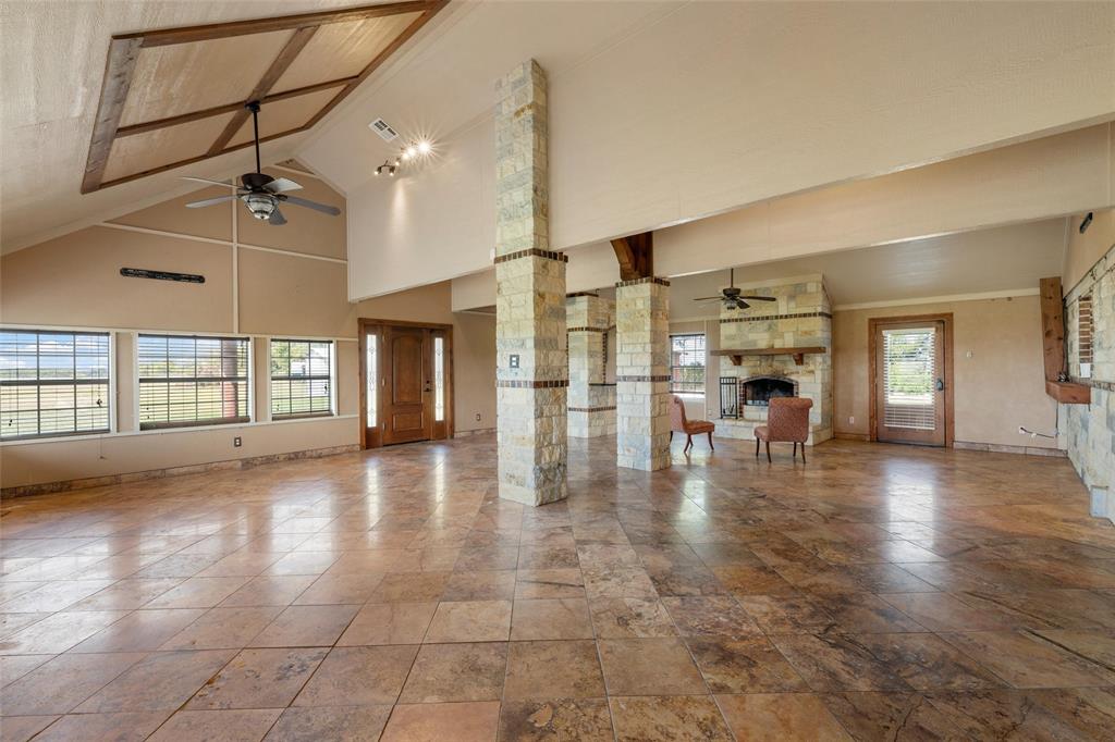 3433 West Tours Road West, TX 76691 - Photo 18 of 40 Unfurnished living room with ceiling fan, a fireplace, high vaulted ceiling, and ornate columns