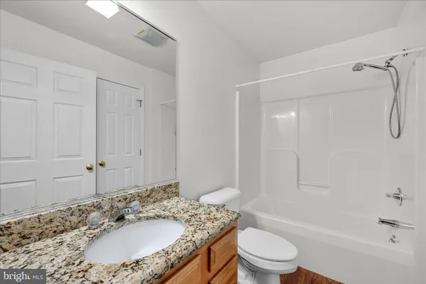 a bathroom with a granite countertop sink toilet and shower