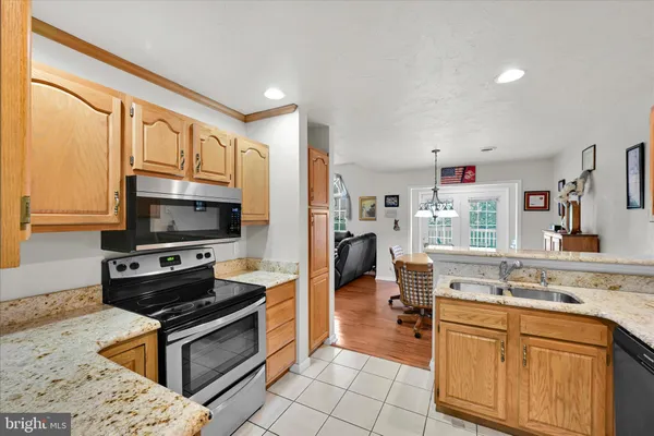 a kitchen with stainless steel appliances granite countertop a stove top oven a sink dishwasher a dining table and chairs with wooden floor