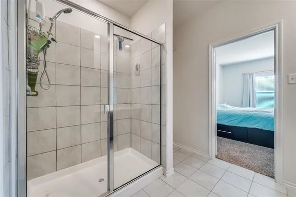 a spacious bedroom with a bed and a flat tv screen on a dresser