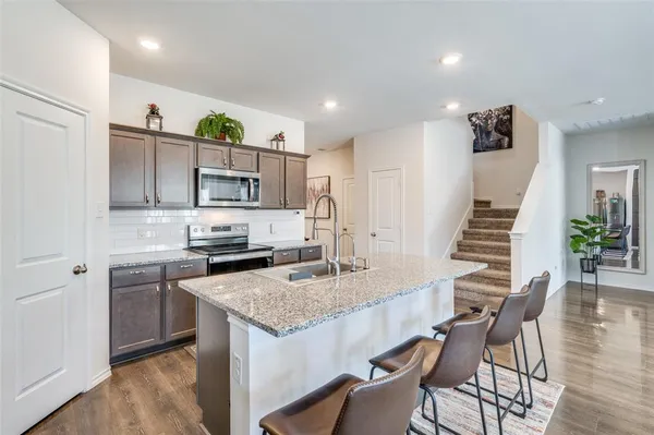 a kitchen with granite countertop a sink stainless steel appliances and cabinets