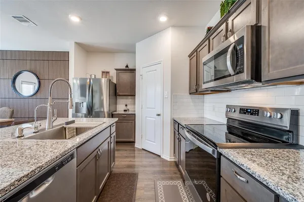 a kitchen with granite countertop kitchen island stainless steel appliances a stove top oven a sink a dining table and chairs