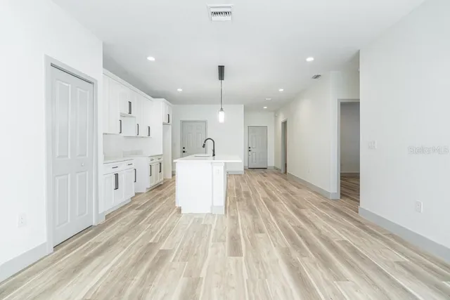 a large white kitchen with kitchen island a sink stainless steel appliances and cabinets