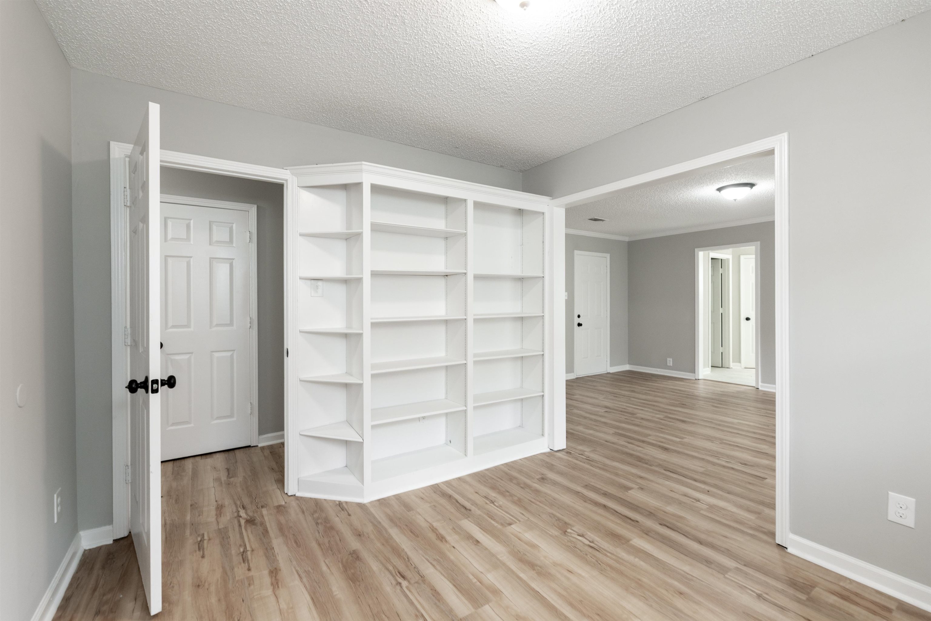 7421 Richmond Road Memphis, TN 38125 - Photo 20 of 39 Integrated corner shelving unit, wood-finish flooring, light gray wall paint, white trim, and a semi-flush ceiling light fixture