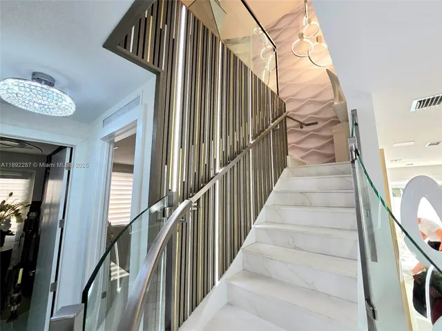 a view of staircase with lots of frames on wall and a large window
