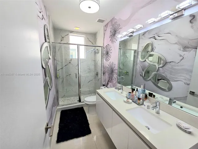 a bathroom with a double vanity sink a toilet a mirror and shower
