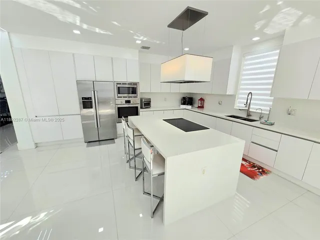 a kitchen with a sink a stove a refrigerator and white cabinets
