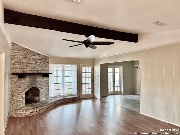 a view of an empty room with wooden floor fireplace and a window