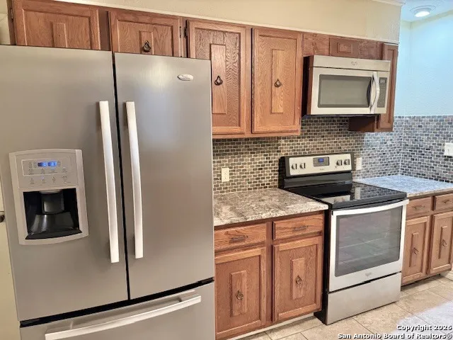 a kitchen with stainless steel appliances granite countertop a refrigerator and a stove