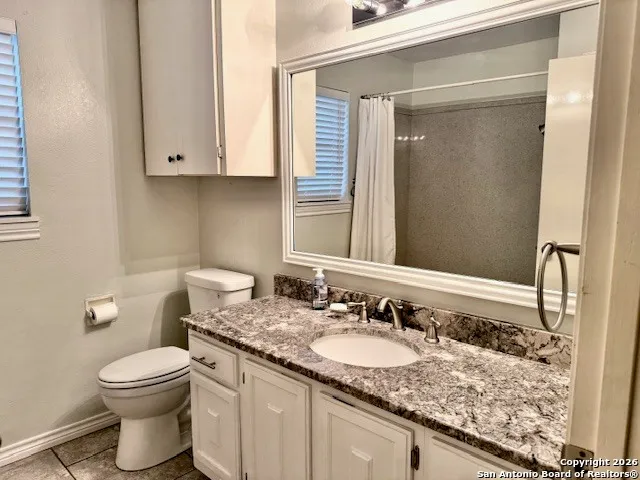 a bathroom with a granite countertop sink a toilet and a mirror