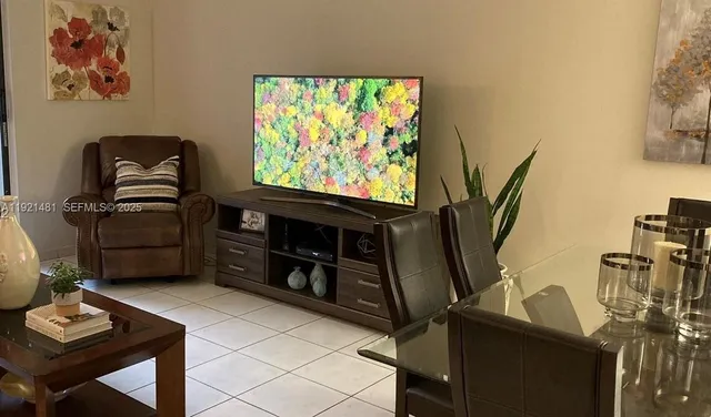 a living room with furniture a flat screen tv and a window