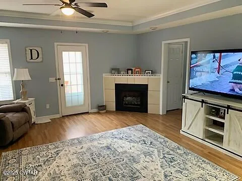 a view of a livingroom with a fireplace a ceiling fan and windows