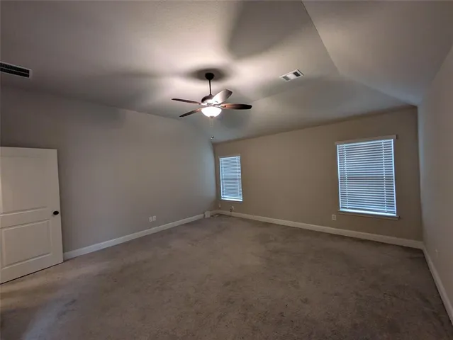 an empty room with a chandelier fan and windows