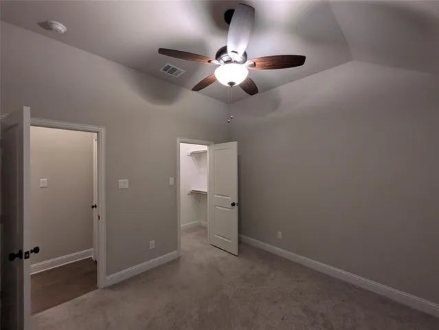 an empty room with closet and a chandelier fan