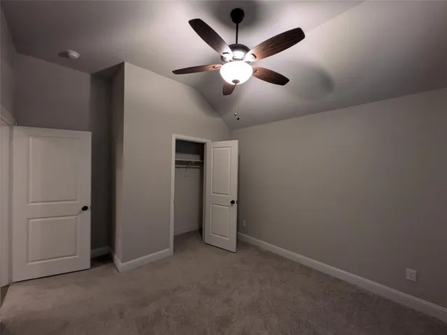 a view of an empty room with a chandelier fan