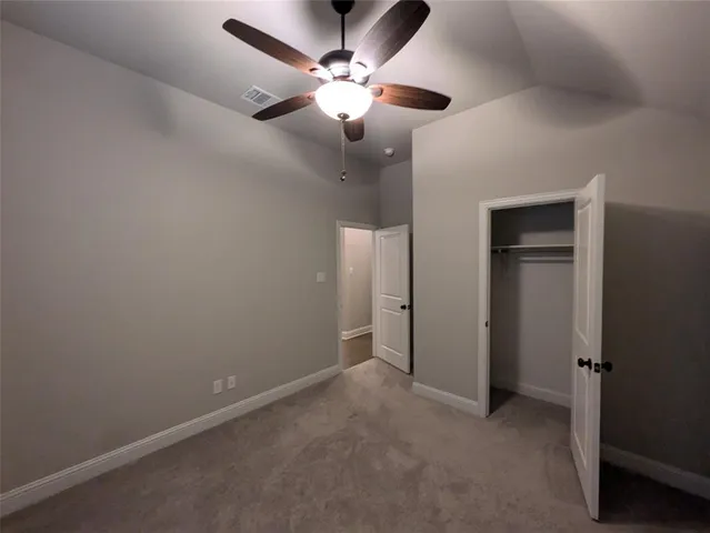 an empty room with closet and a chandelier fan