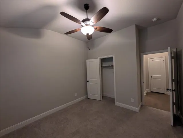 an empty room with closet and a chandelier fan