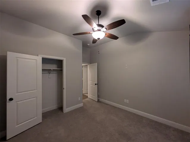 an empty room with closet and a chandelier fan