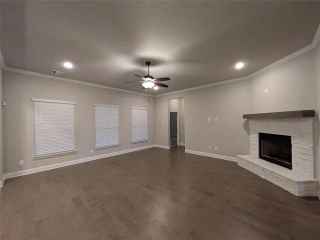 an empty room with a fireplace and chandelier fan
