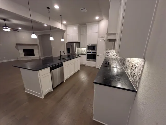 a kitchen with stainless steel appliances kitchen island granite countertop a sink a stove and a refrigerator