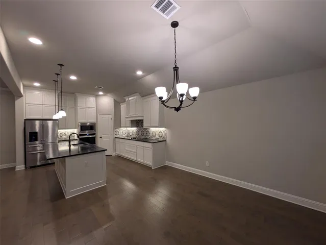 a kitchen with stainless steel appliances granite countertop a sink a stove and a wooden floor