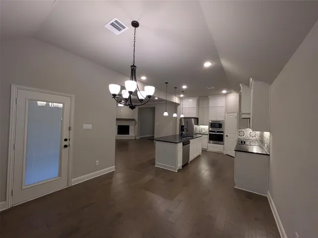 a view of a dining room and livingroom with furniture wooden floor a chandelier