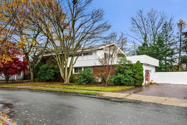 a view of a house with a yard and large trees