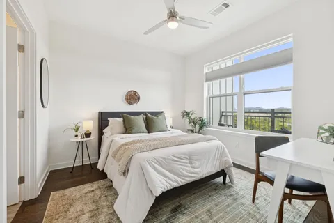a bedroom with a bed a table and chair with the wooden floor