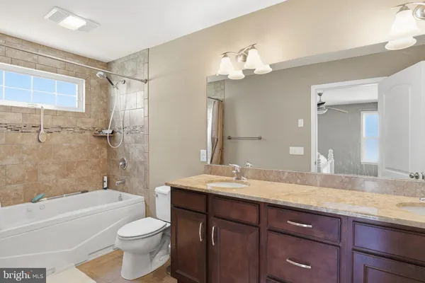 a bathroom with a double vanity sink toilet mirror and bathtub
