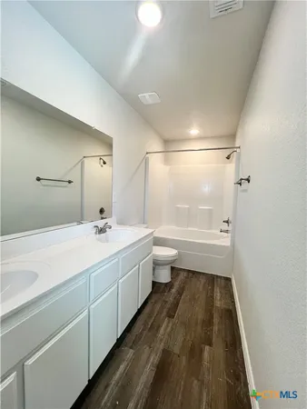 a bathroom with a double vanity sink a toilet and a tub